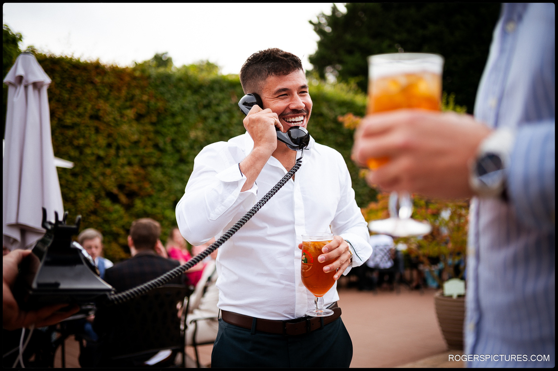 Guest smiling and speaking into the retro-style phone recording a message while holding a drink.