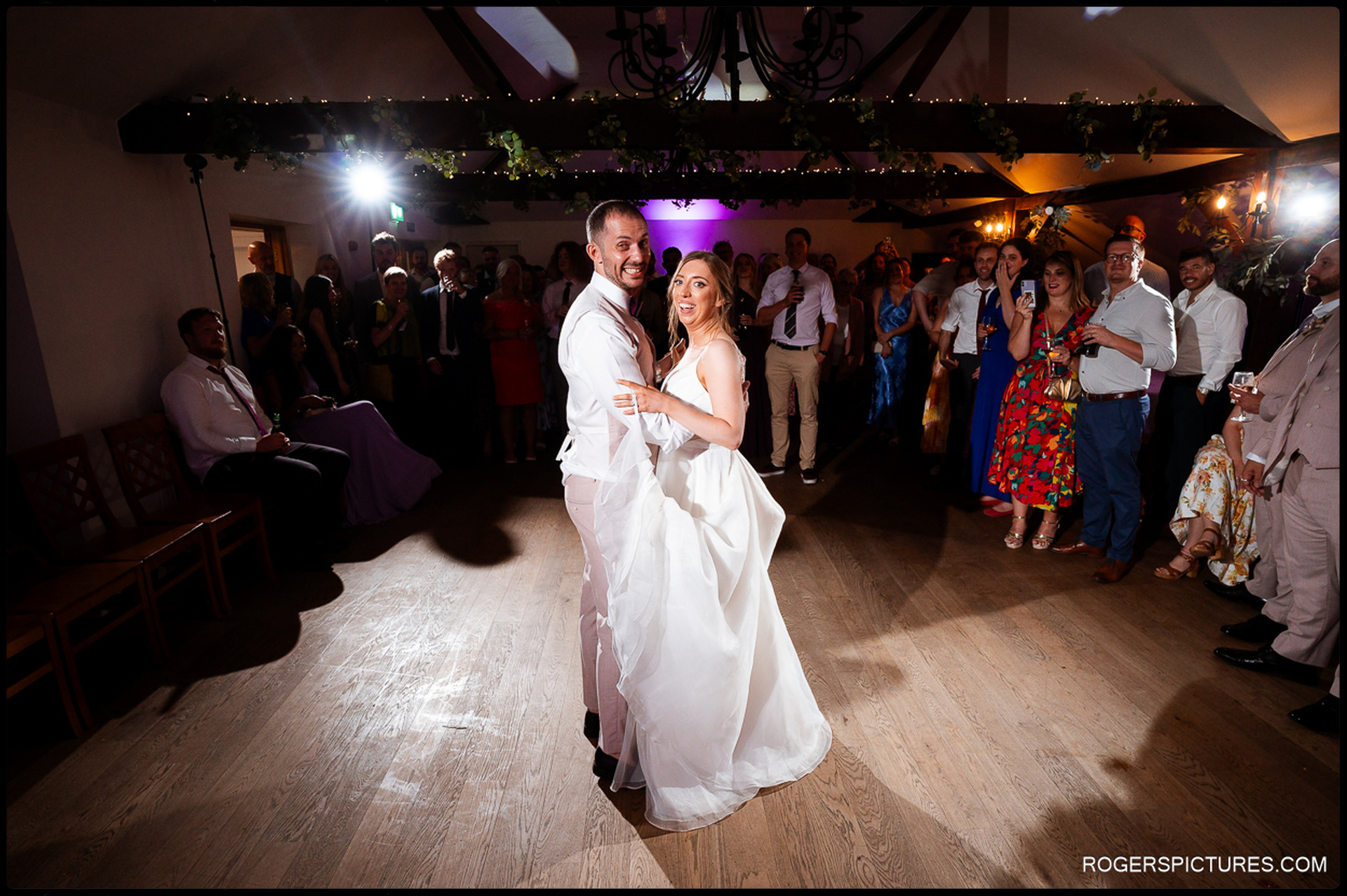 Bride and groom dancing their first dance surrounded by friends and family.