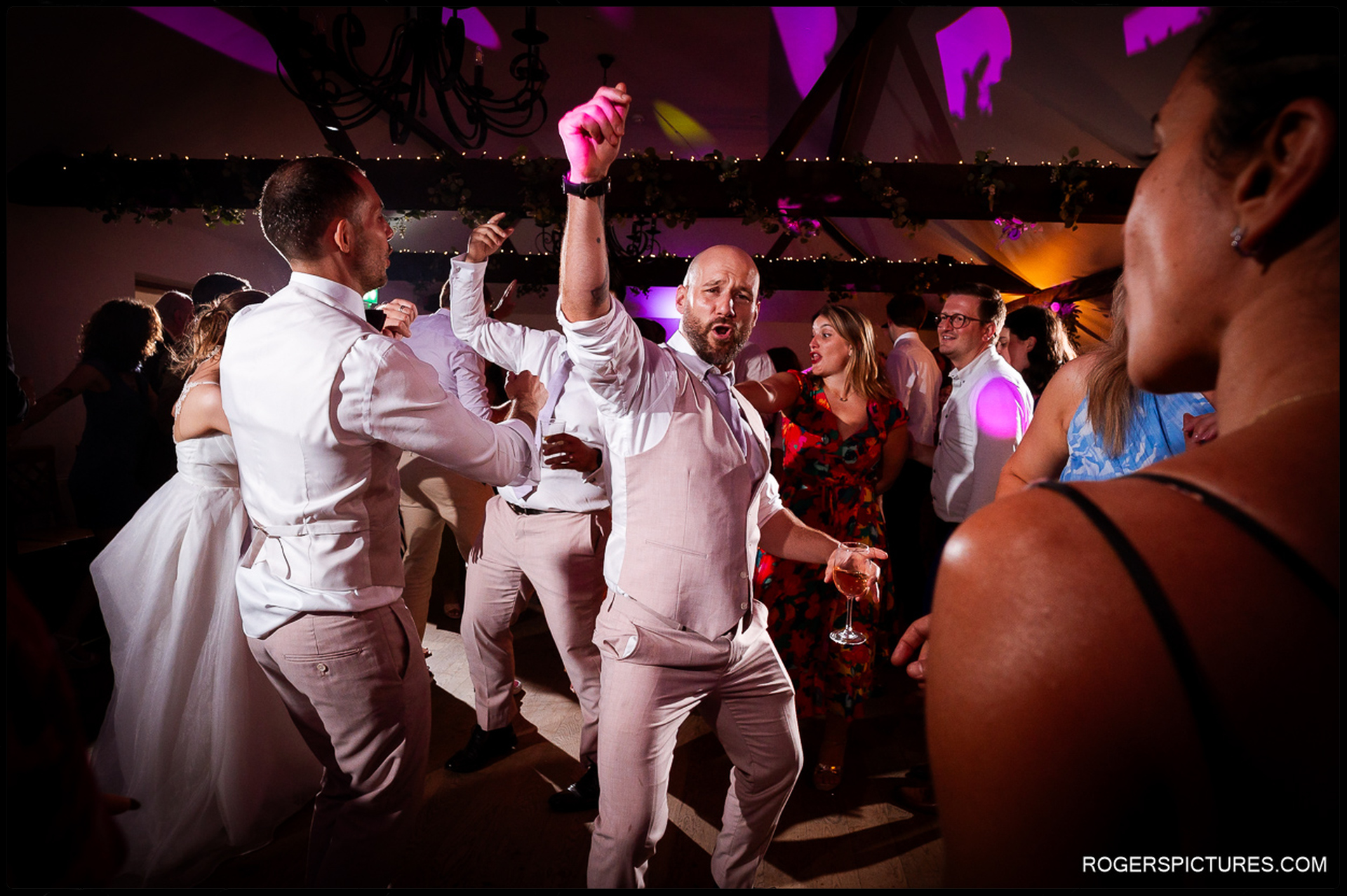 Guests dancing enthusiastically on the dance floor under party lights.