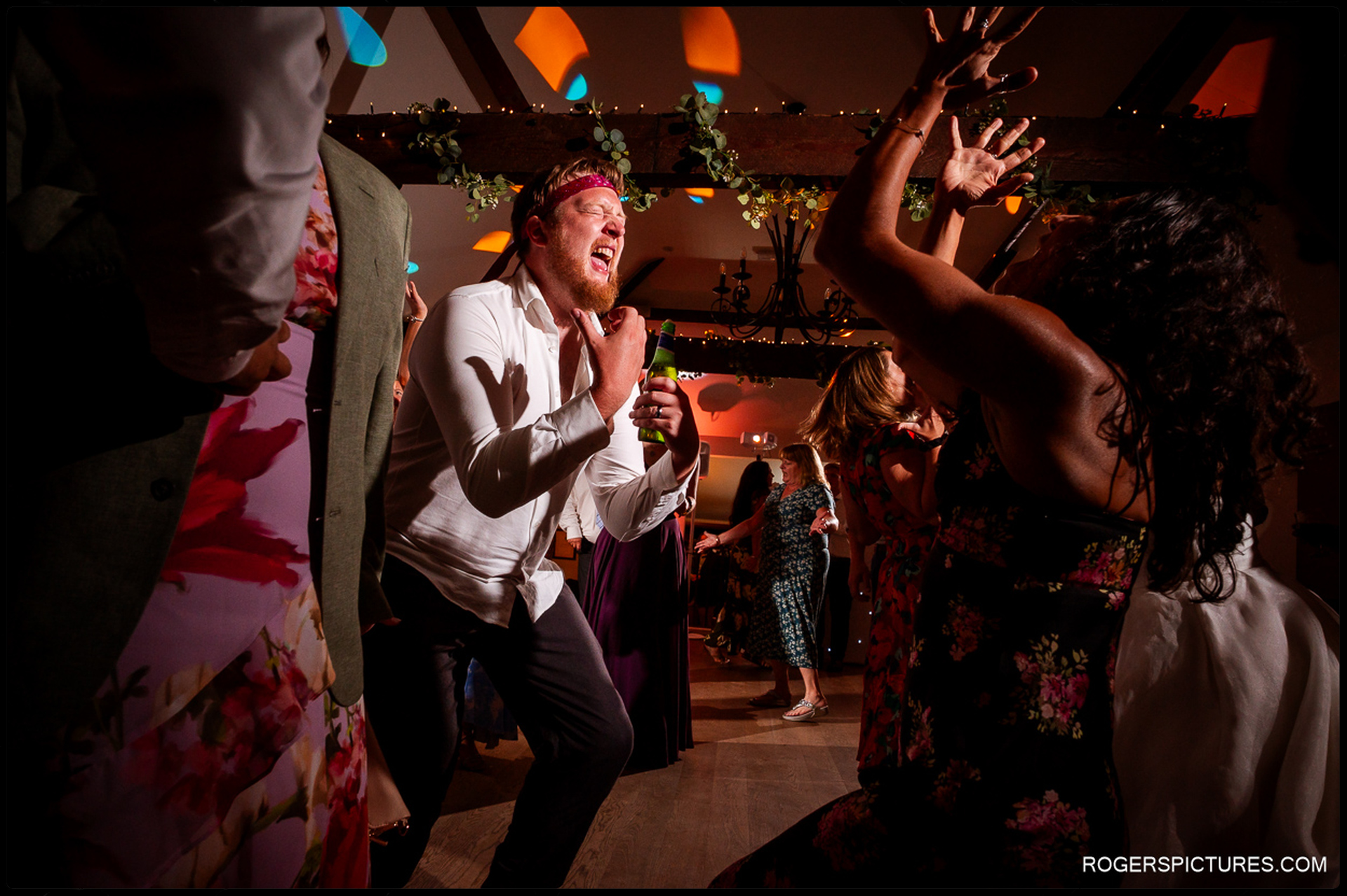 Wedding guests partying on the dancefloor with colourful lights and energetic dancing
