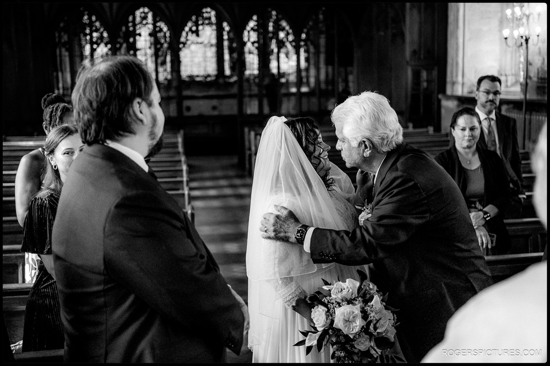 Bride’s father gives her an emotional kiss before the ceremony inside St Etheldreda’s Church, surrounded by wooden pews and stained-glass windows.