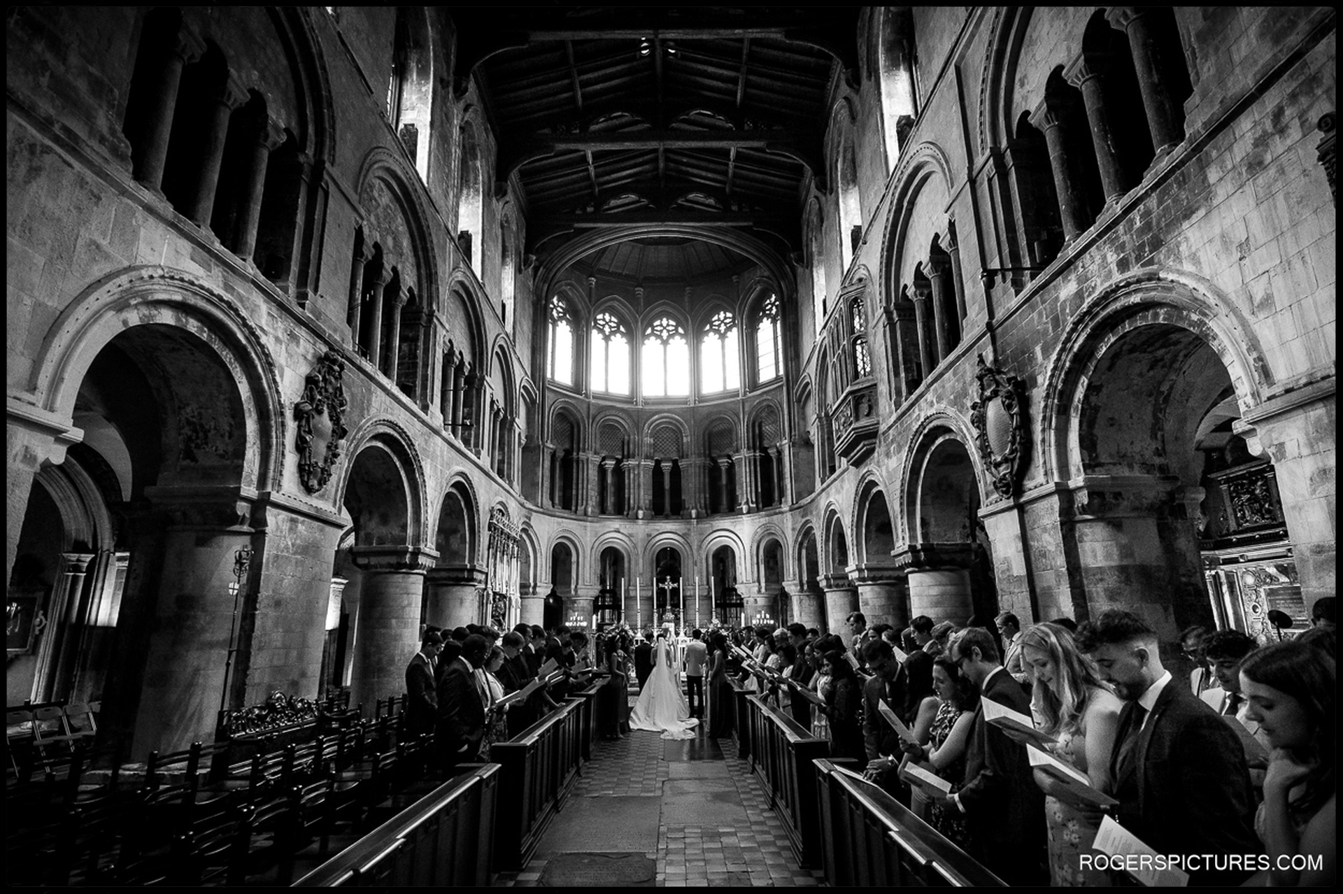 Wide black and white view of the wedding ceremony inside St Bartholomew the Great