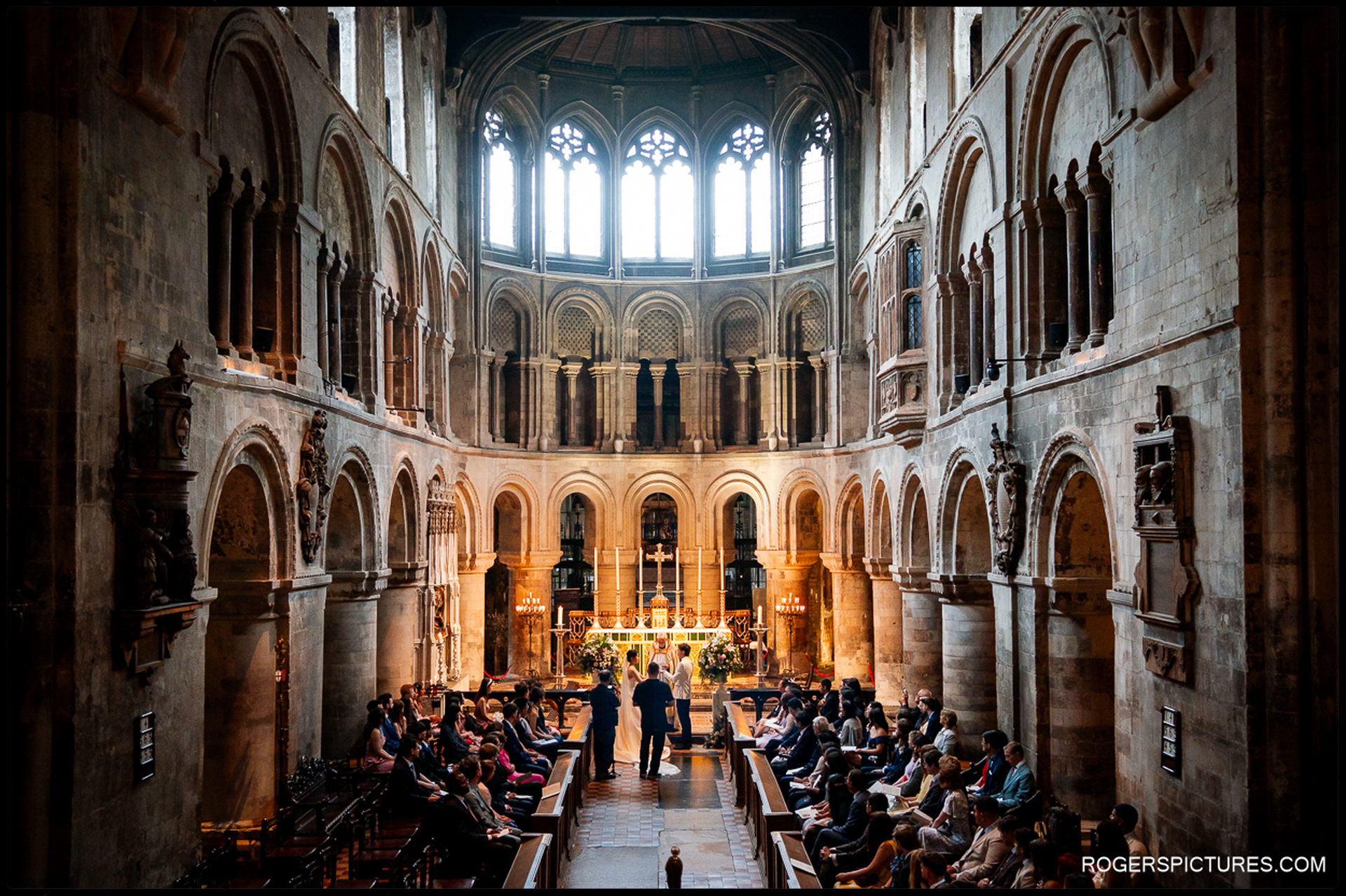 Guests seated as the couple stand at the altar during the ceremony at St Bartholomew the Great