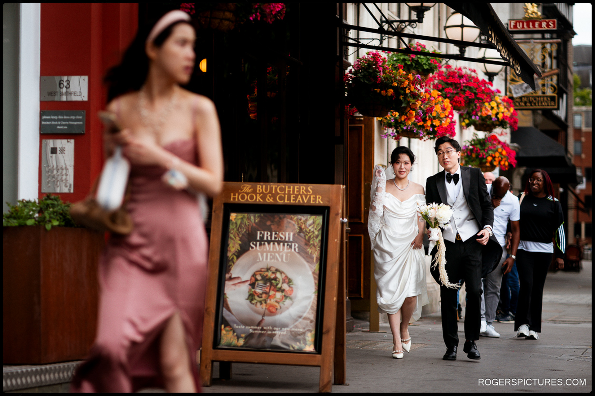 Couple walking past shops and hanging flowers near the Butchers Hook and Cleaver