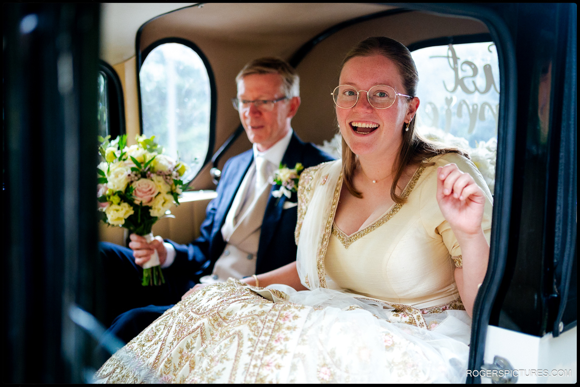 Bride and her father sit in the wedding car, holding flowers and smiling before leaving for the church.