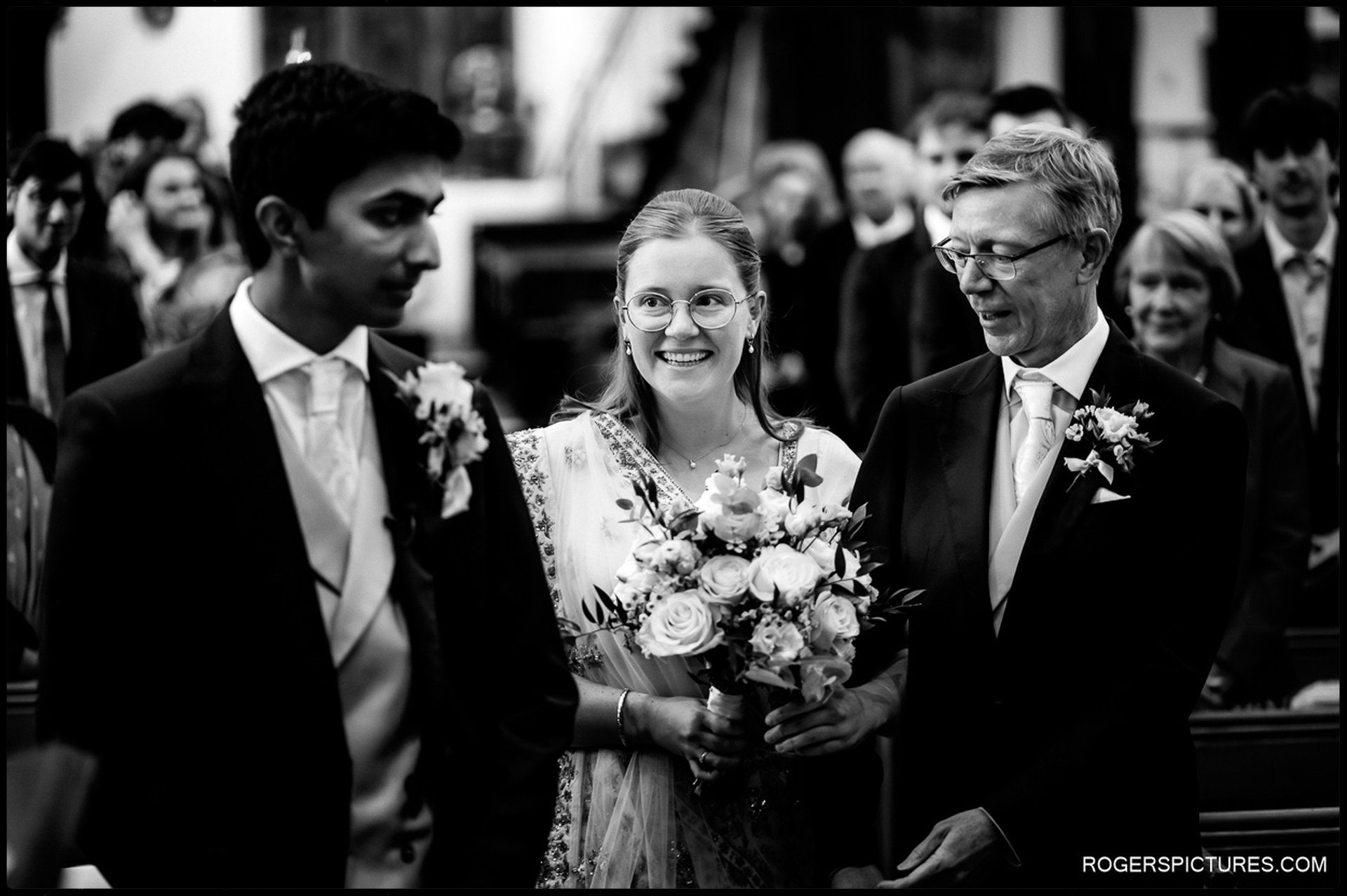 Bride smiles at the groom at the front of the church during the start of the ceremony.