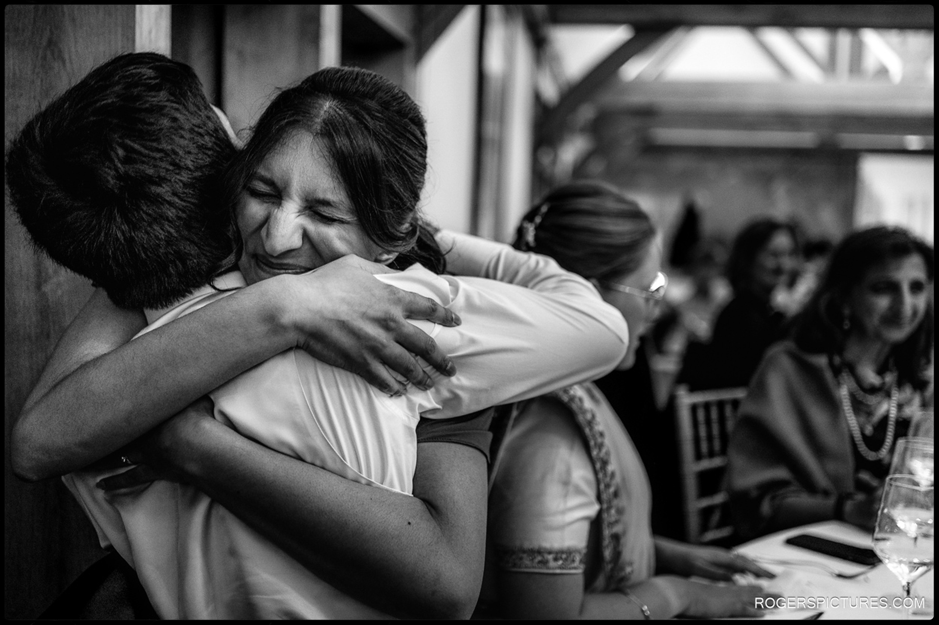 Groom hugs a guest tightly as she closes her eyes and smiles during the reception.