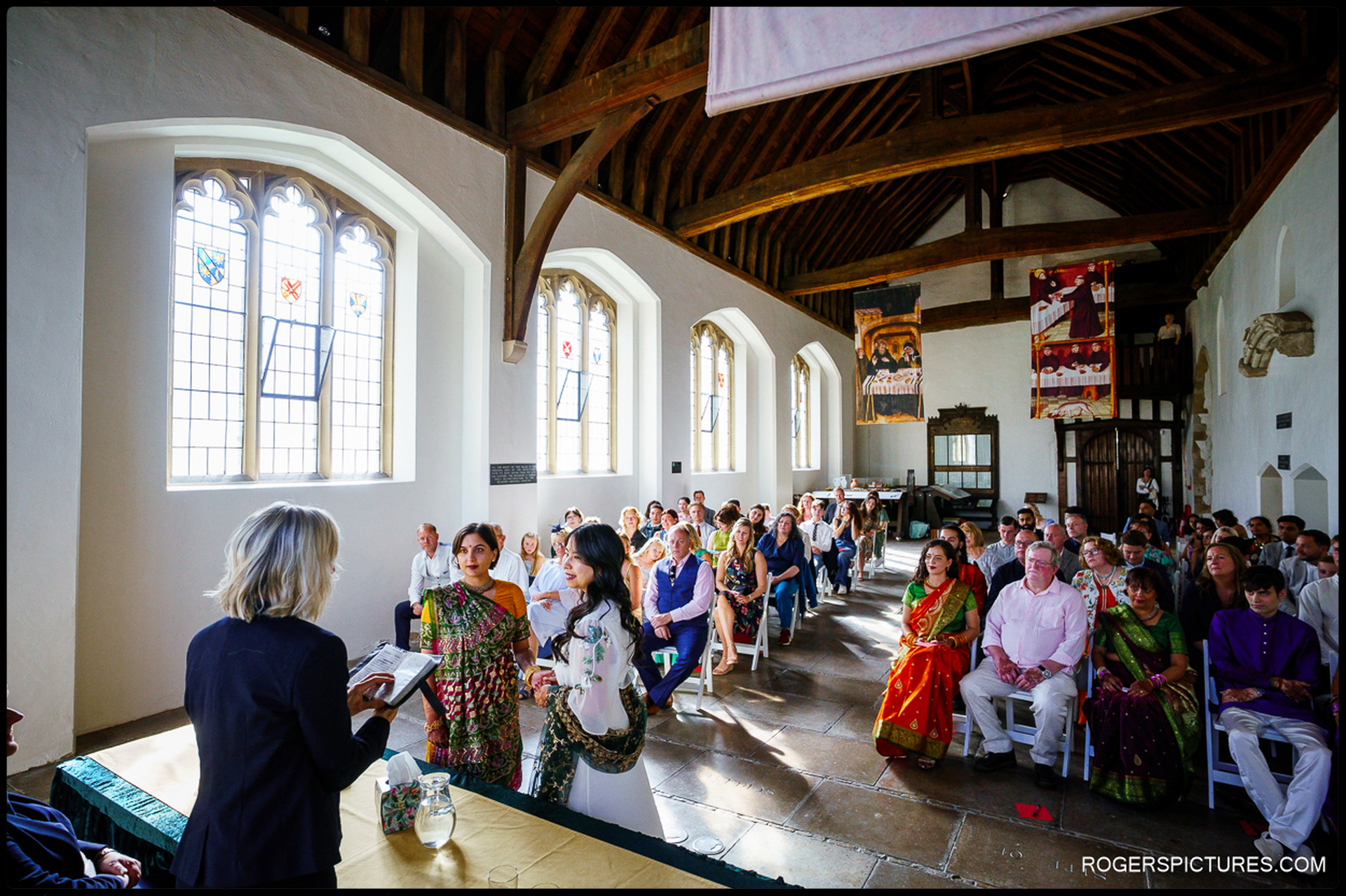 Civil ceremony at Prittlewell Priory with couple holding hands and guests seated in historic hall