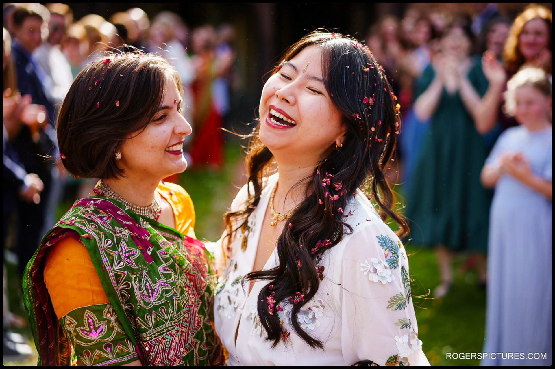 Two brides laughing together covered in confetti after their ceremony at Prittlewell Priory