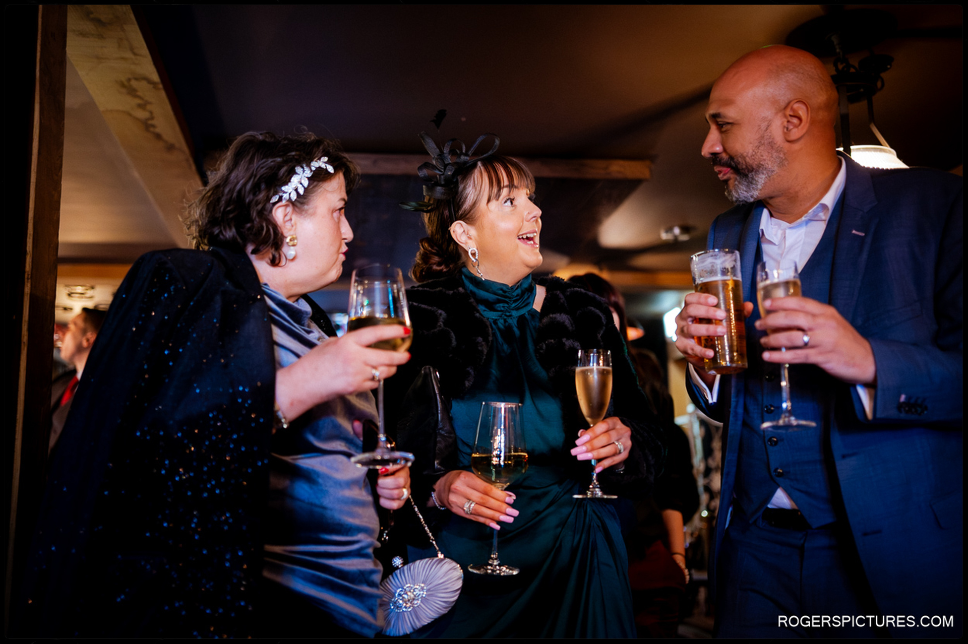 Guests socializing and enjoying champagne and drinks in the dimly lit, atmospheric interior of The Bell during the twilight hours.