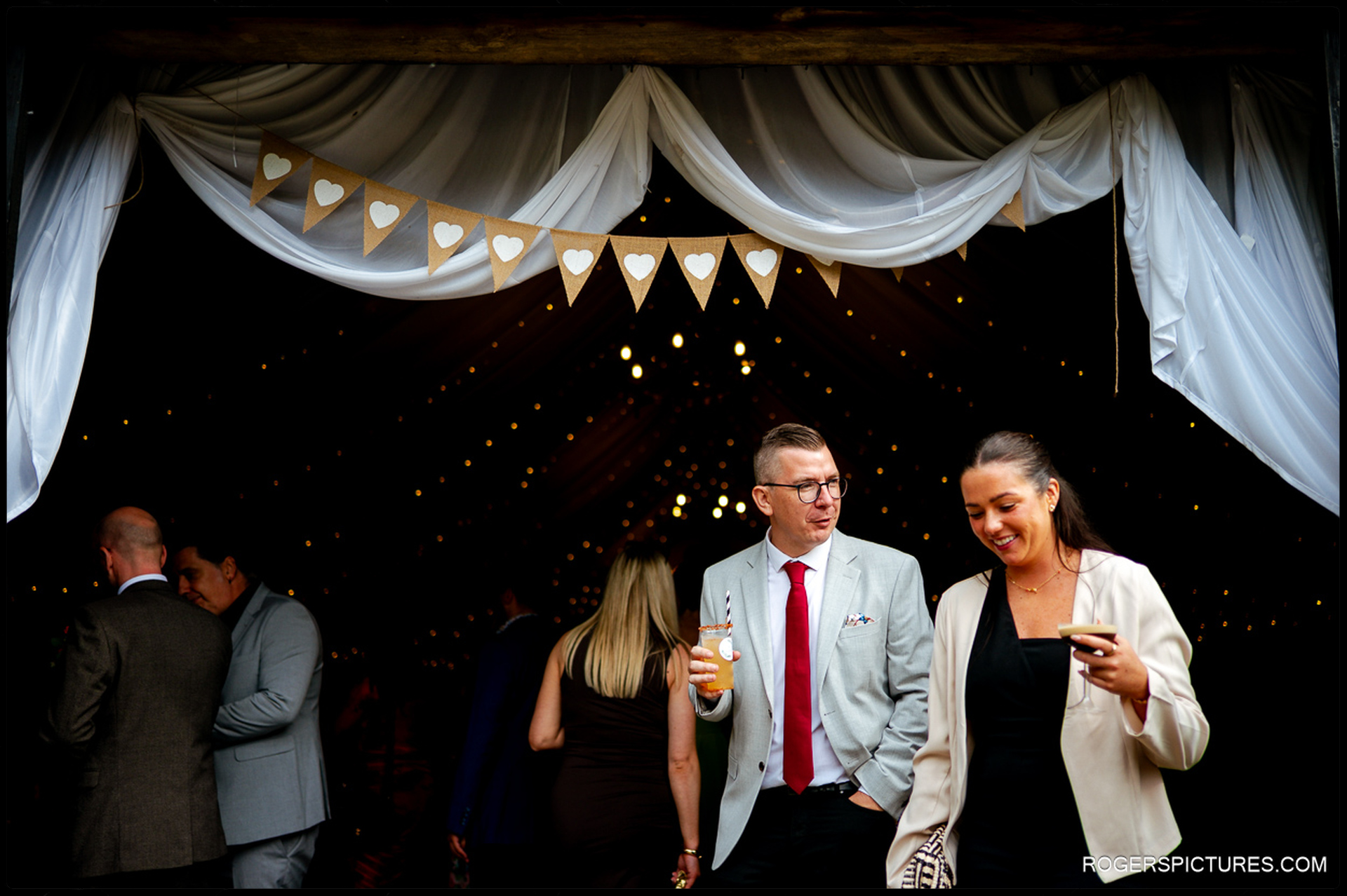Guests chatting and enjoying cocktails outside the decorated barn at Rumbolds Farm.