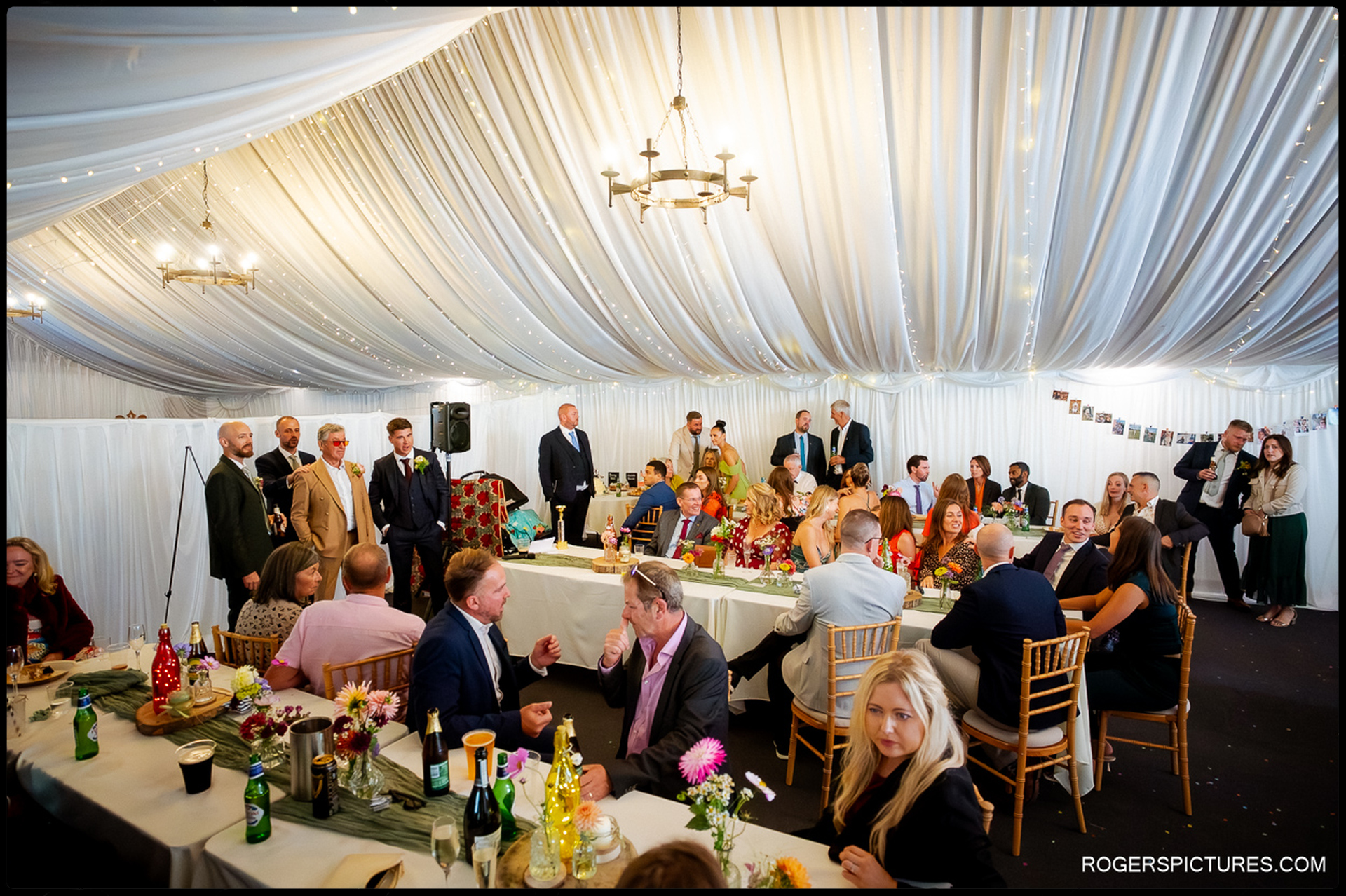 Guests seated under the draped marquee during the wedding breakfast at Rumbolds Farm.