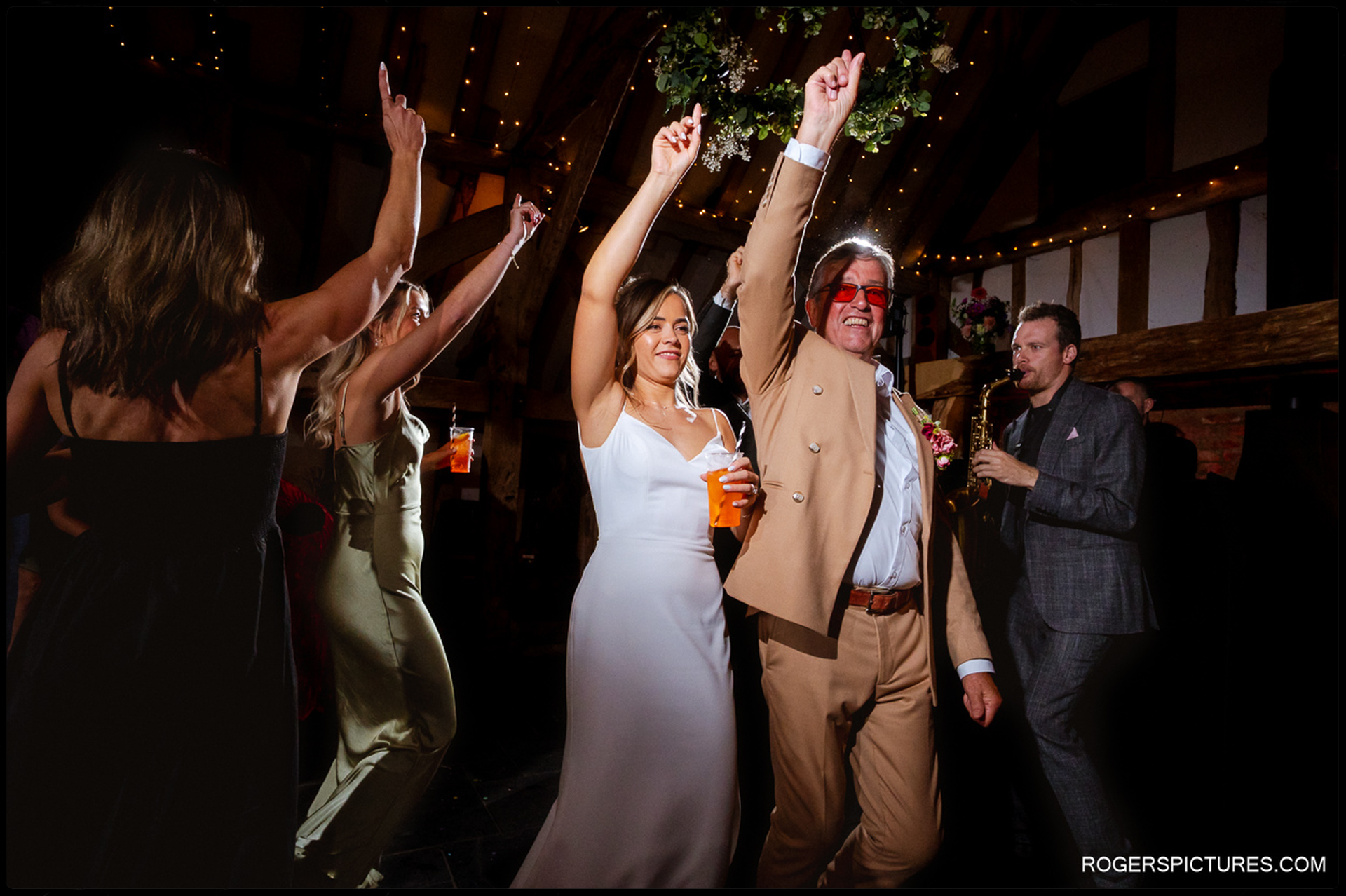 Bride and her father leading guests onto the dance floor as the saxophonist plays at Rumbolds Farm.
