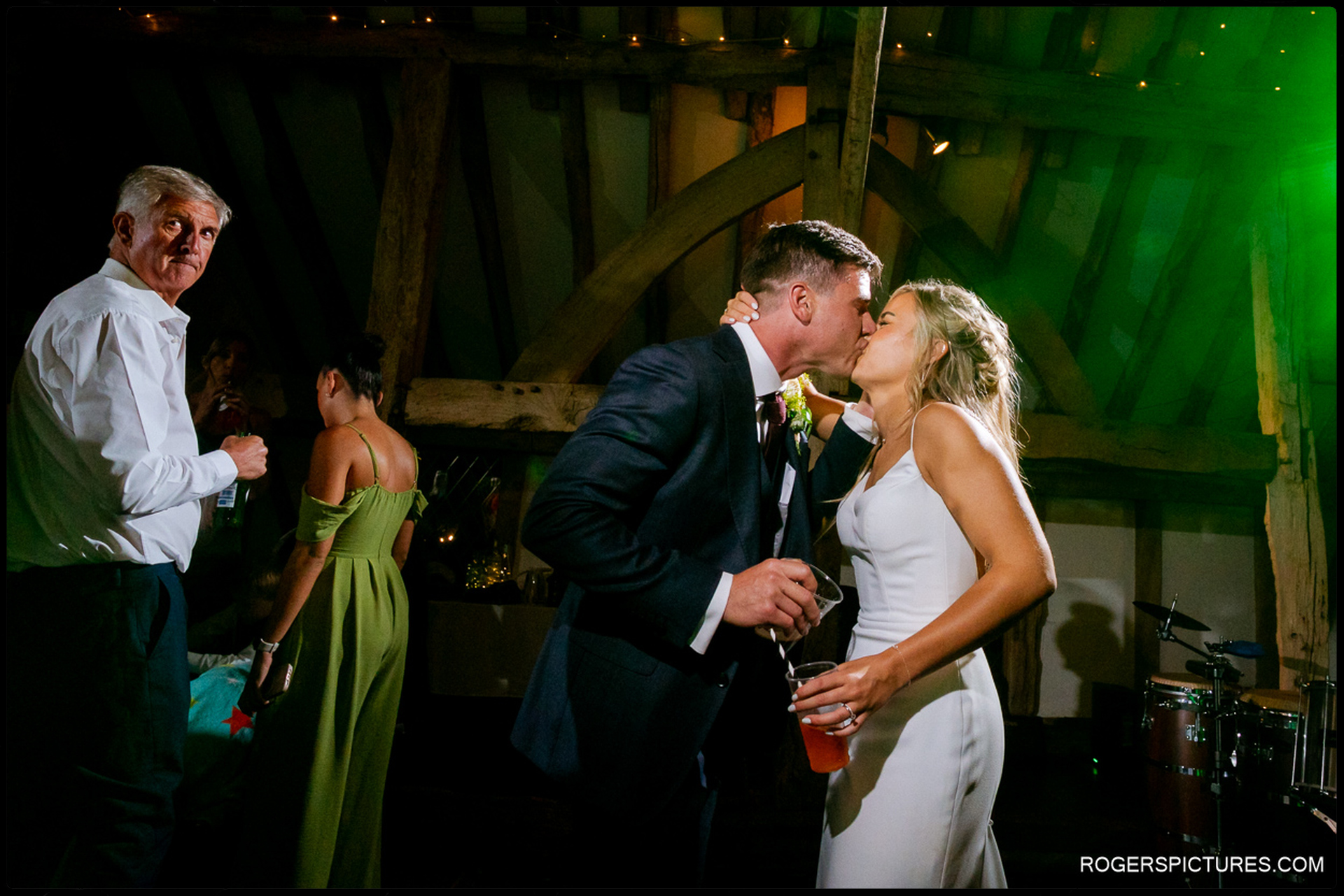 Bride and groom sharing a kiss on the dance floor under green lights at Rumbolds Farm.