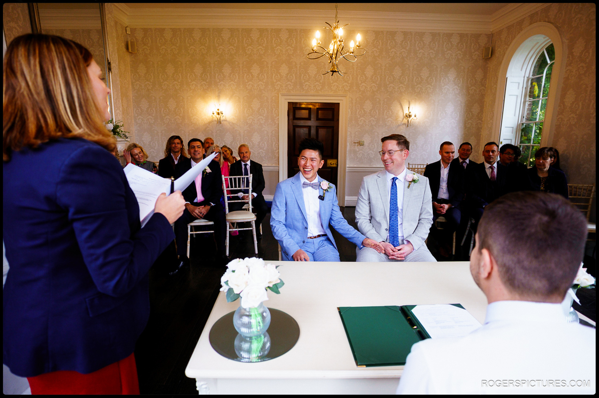 A natural, unposed shot of a couple laughing during their wedding ceremony in the Sheridan Room at Morden Park House.