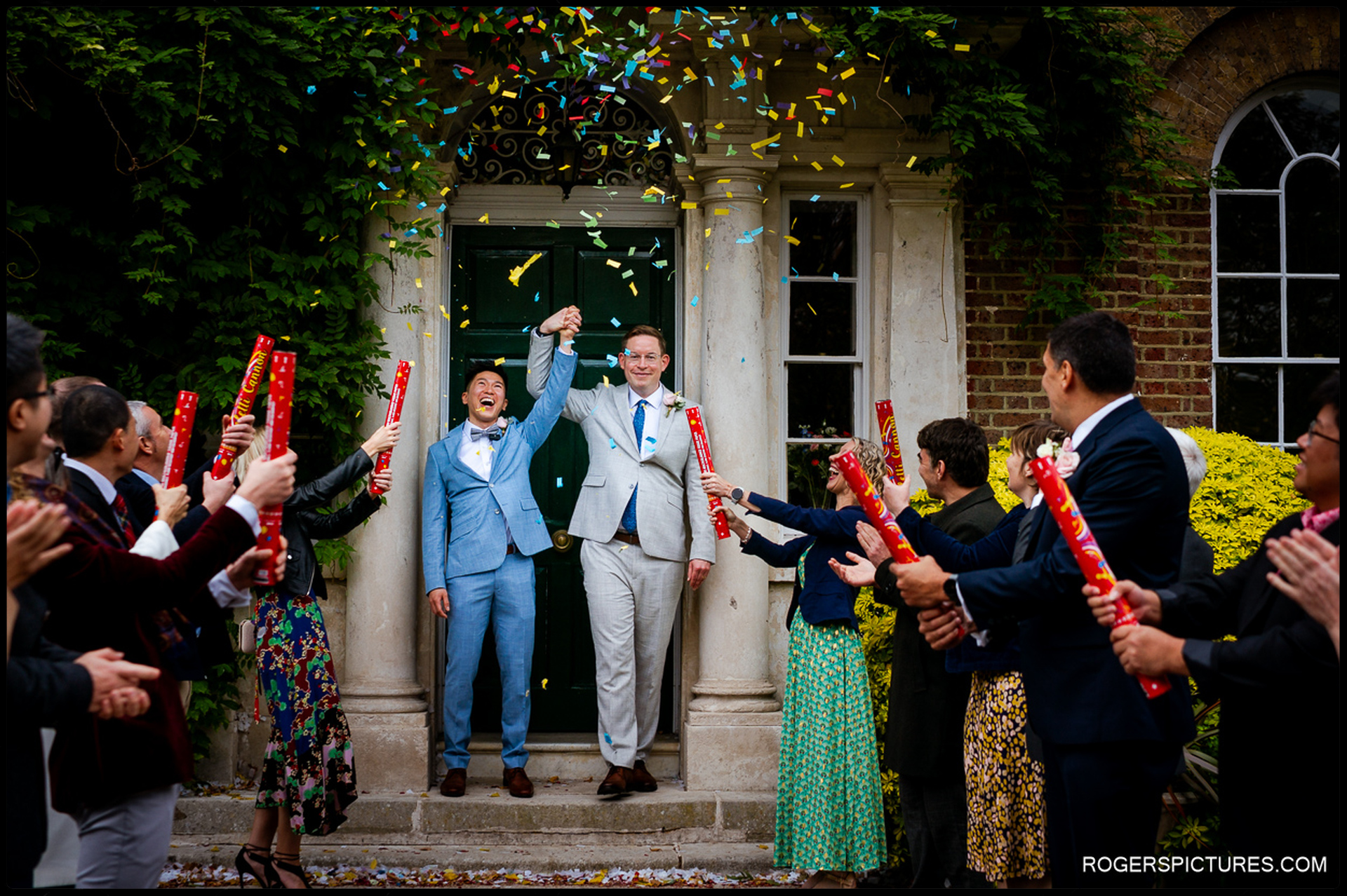 A joyful wedding exit featuring a couple being showered with colourful confetti outside the historic doors of Morden Park House.
