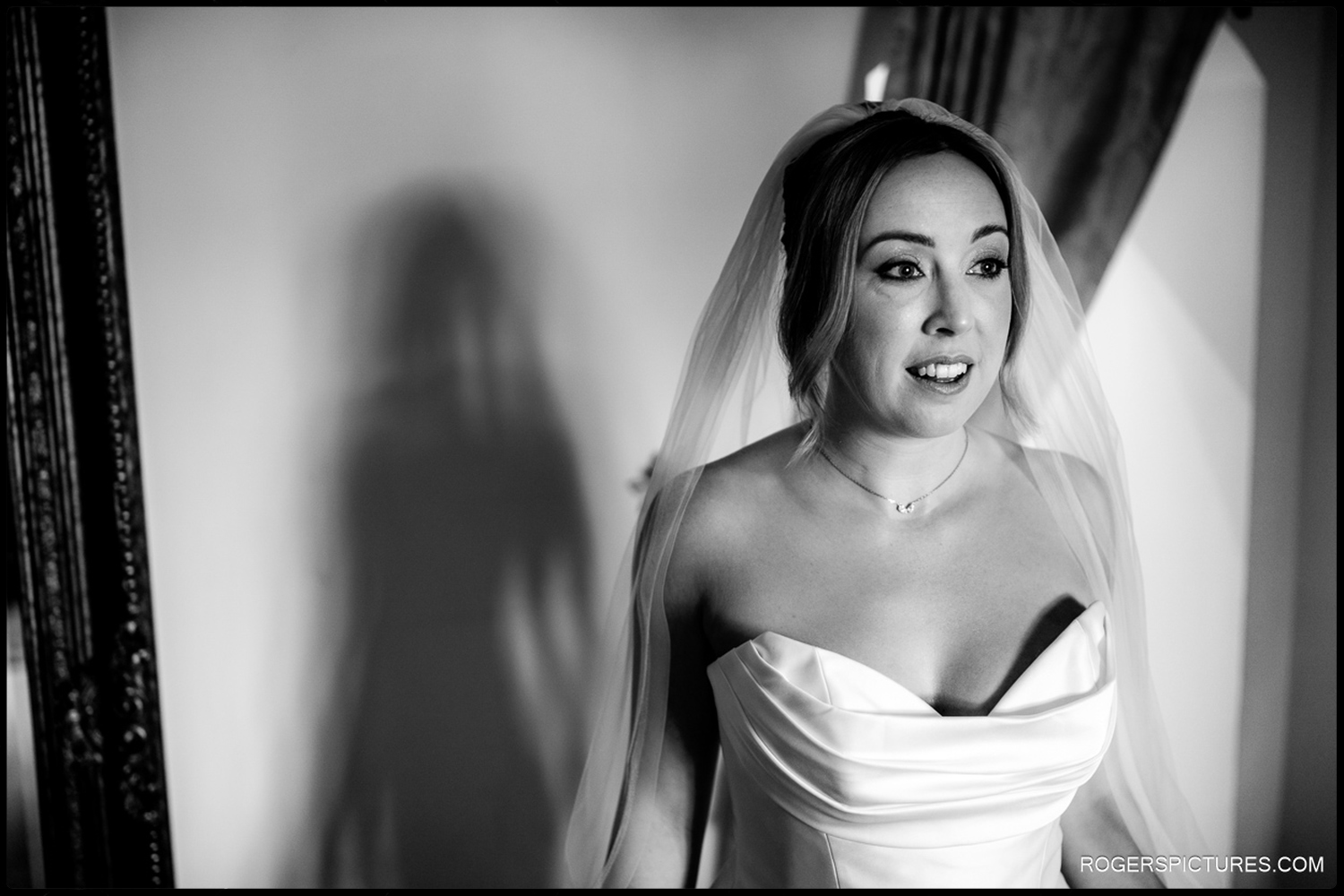 A black and white natural portrait of a bride in her wedding dress and veil, captured during the morning preparations at an exclusive Suffolk venue.