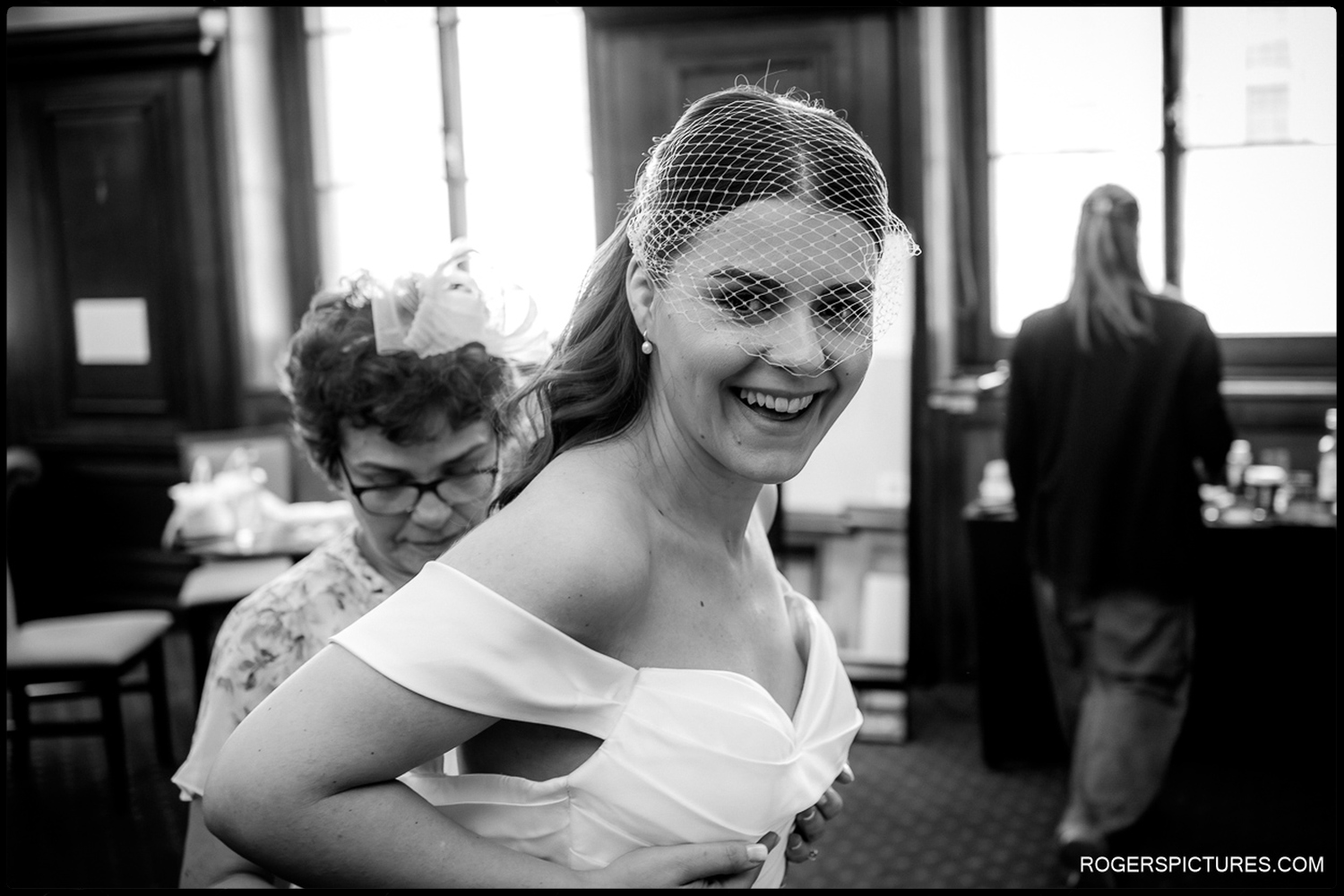 A black and white natural moment capturing a bride's joyful expression as her dress is fastened during her wedding preparations at The Law Society.