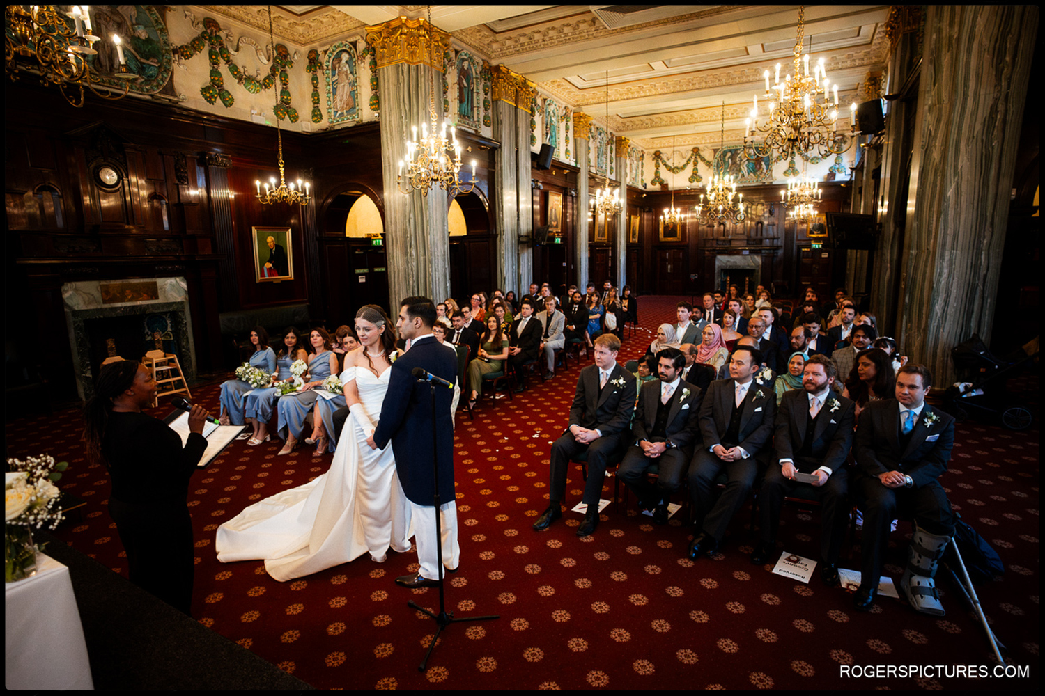A wide-angle photograph capturing the scale of the ceremony room at 113 Chancery Lane, with guests seated in rows as the couple stands at the front.
