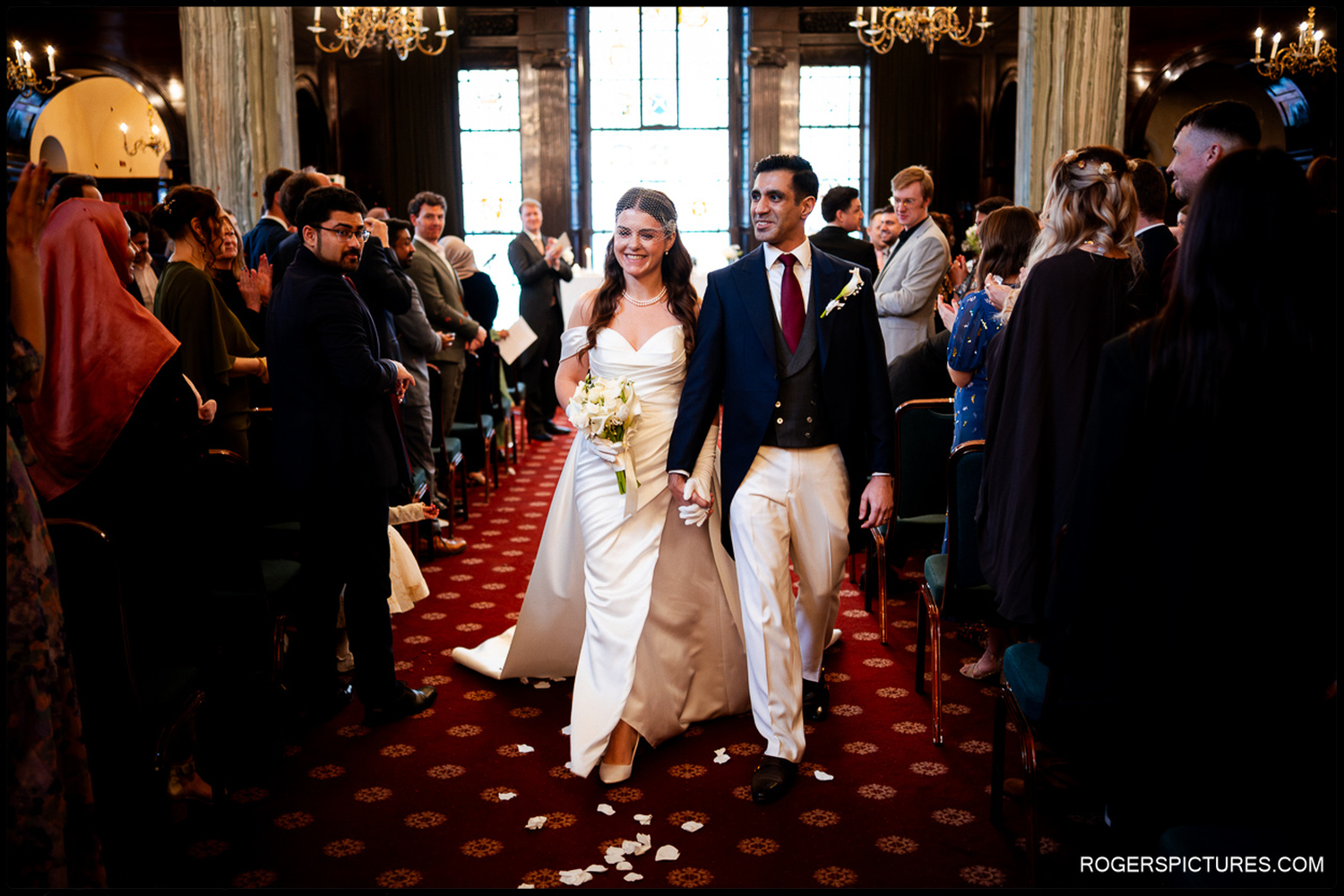 A natural, unposed shot of the happy couple smiling as they walk back down the aisle together after their winter wedding ceremony.