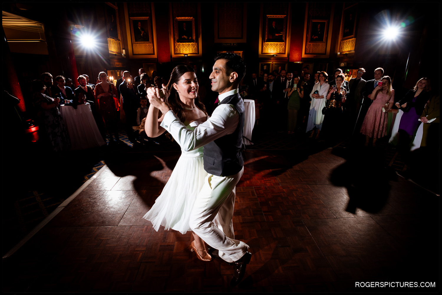 A joyful unposed moment of the couple smiling at each other while dancing on a wooden dance floor during their winter wedding reception in London.